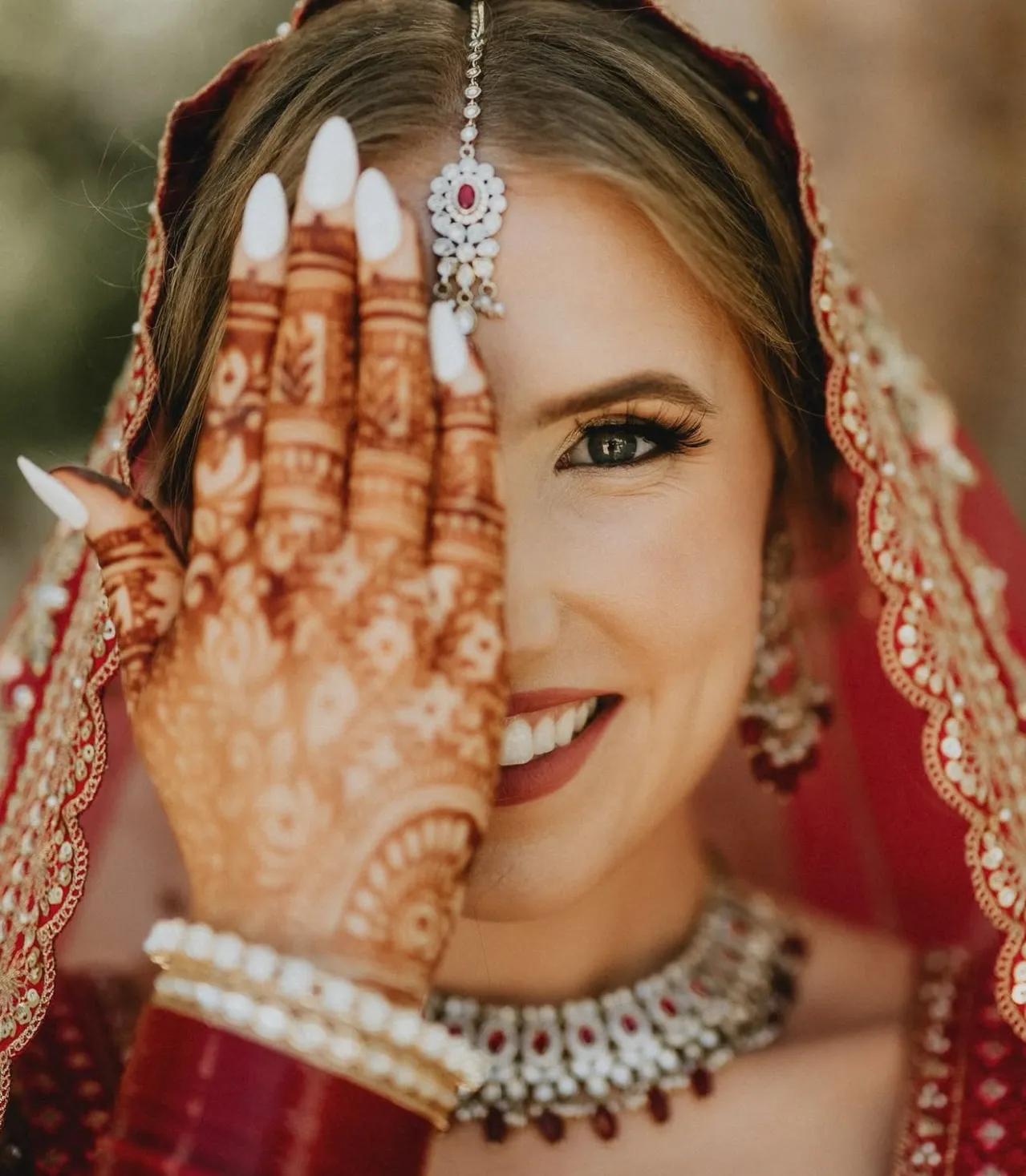 South Asian bridal portrait with henna and red veil