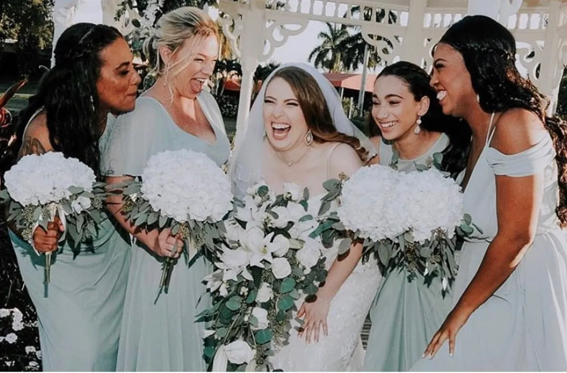 Bridal party laughing with white bouquets